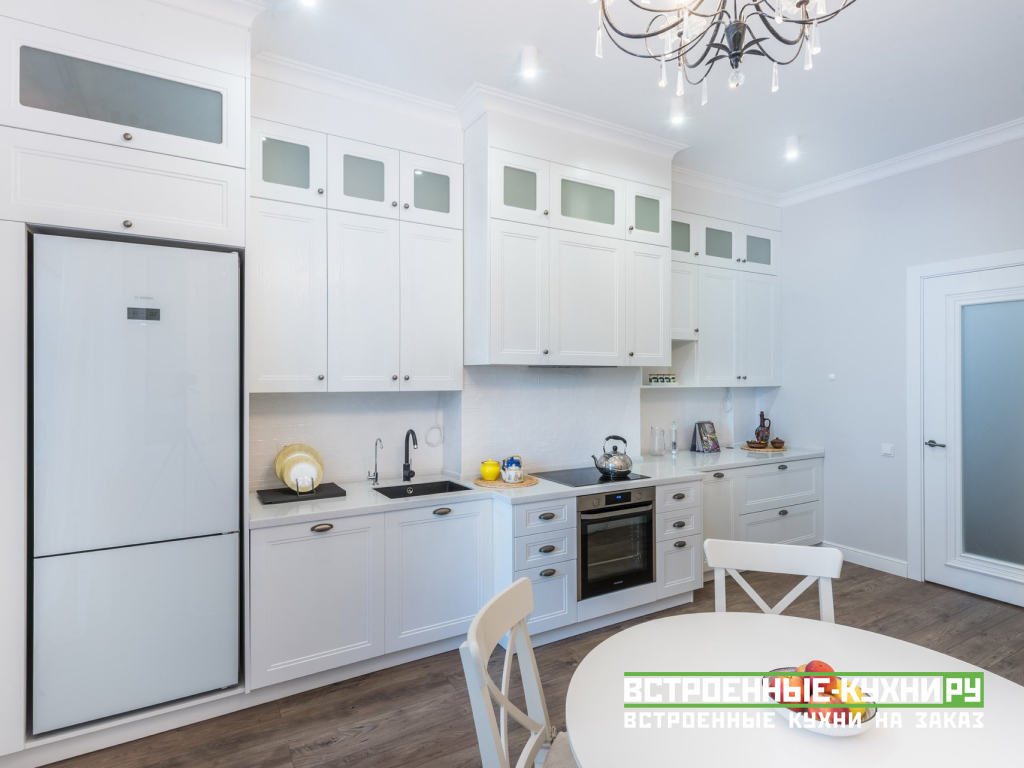 Белая прямая кухня со встроенным холодильником с антресолями